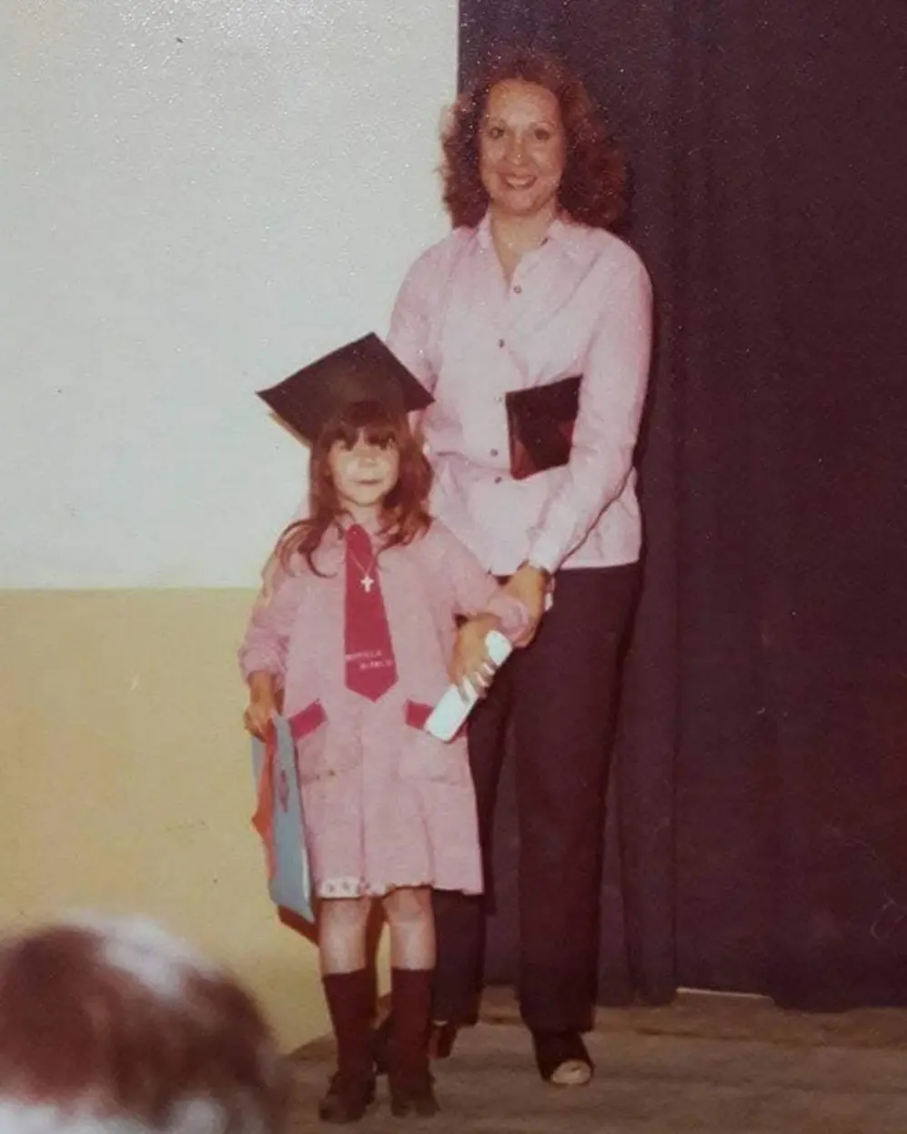 Mariela Blanco con birrete y diploma junto a su madre en un evento escolar
