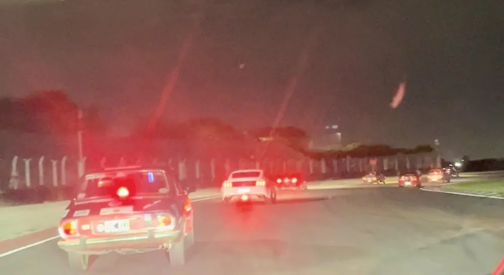 La noche es borrosa en la pista y en las fotos. A los lejos, un Mustang.