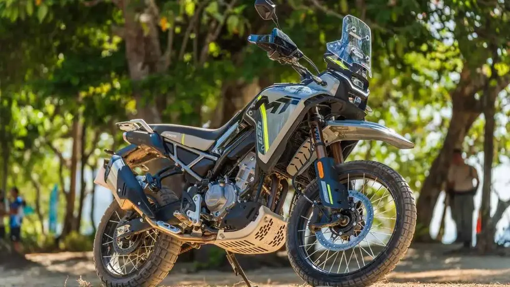 Moto de la marca CFMoto de frente y perfil con árboles de fondo