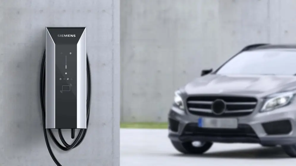 Cargador eléctrico en pared y auto de fondo. Foto oficial.