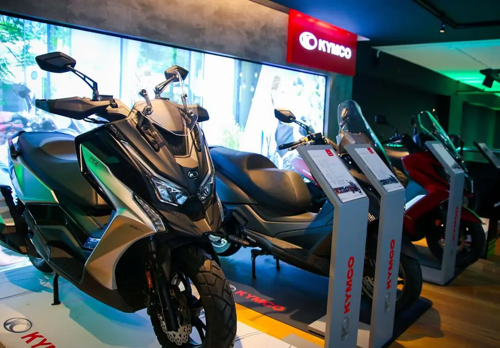 Scooters Kymco de distintos modelos y colores exhibidos en una concesionaria.