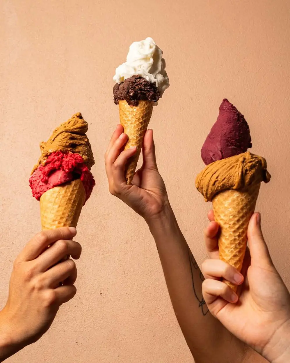 Tres manos alzando cucuruchos con helados de la marca Rapanui