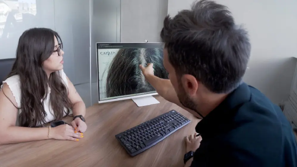 Un profesional de Capilea explcandole a una clienta interesada el tratamiento a traves de una imagen