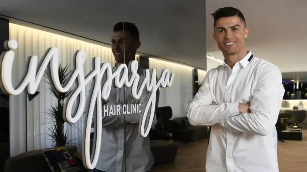 Cristiano ronaldo vestido ropa blanca en una clínica capilar con pared espejada