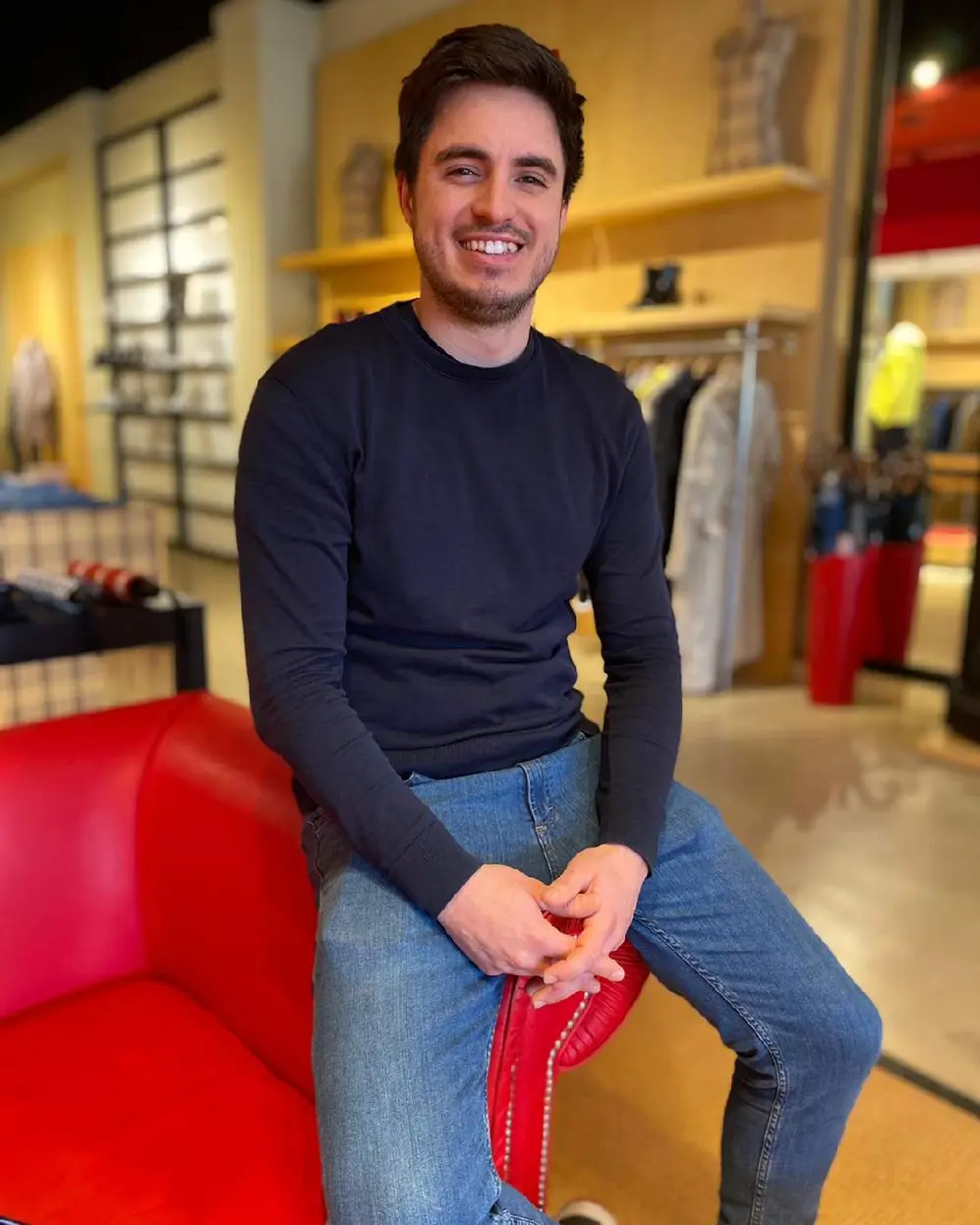 Hombre joven apoyado en un sillón rojo dentro de un local de la marca Hunter