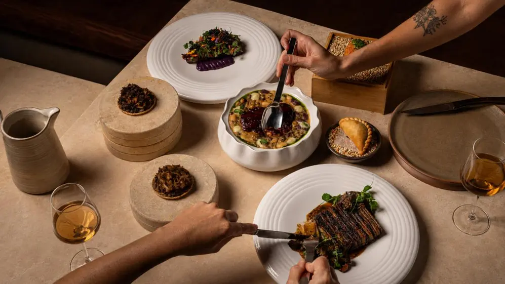 Mesa servida con distintos platos de alta cocina en vajilla blanca (Gentileza Volf)