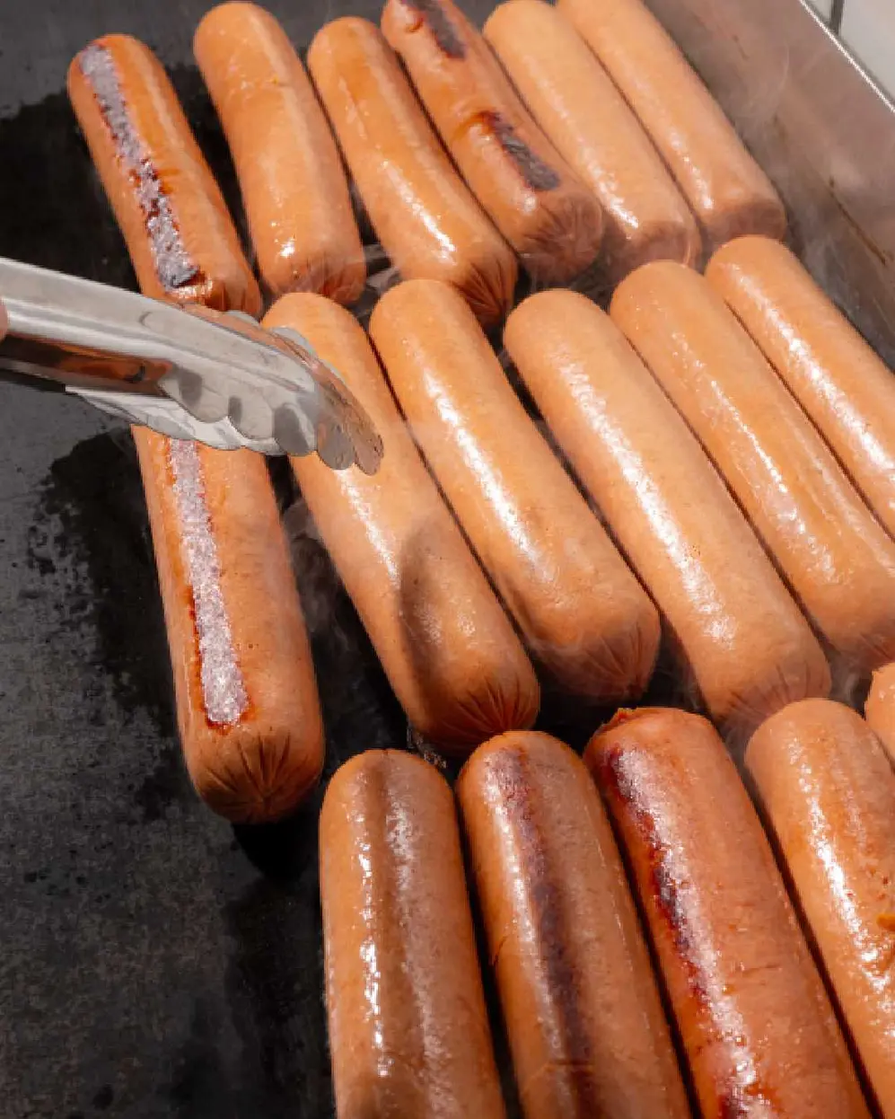 Salchichas arriba de una plancha cocinándose