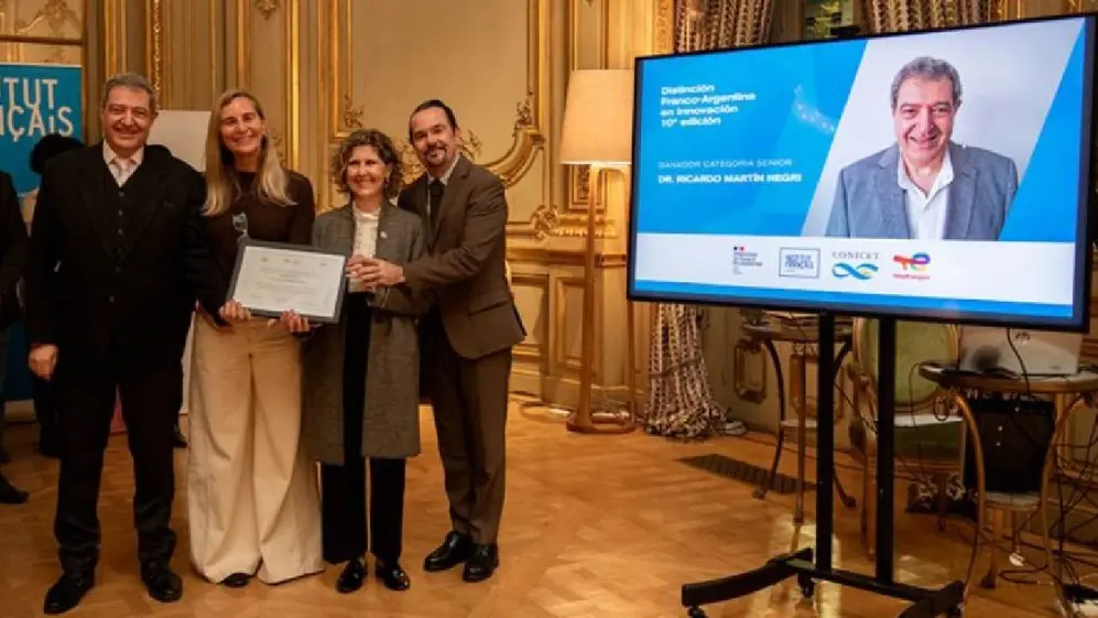 Dos mujeres y dos hombres recibiendo de manera conjunta un diploma y una pantalla a un costado