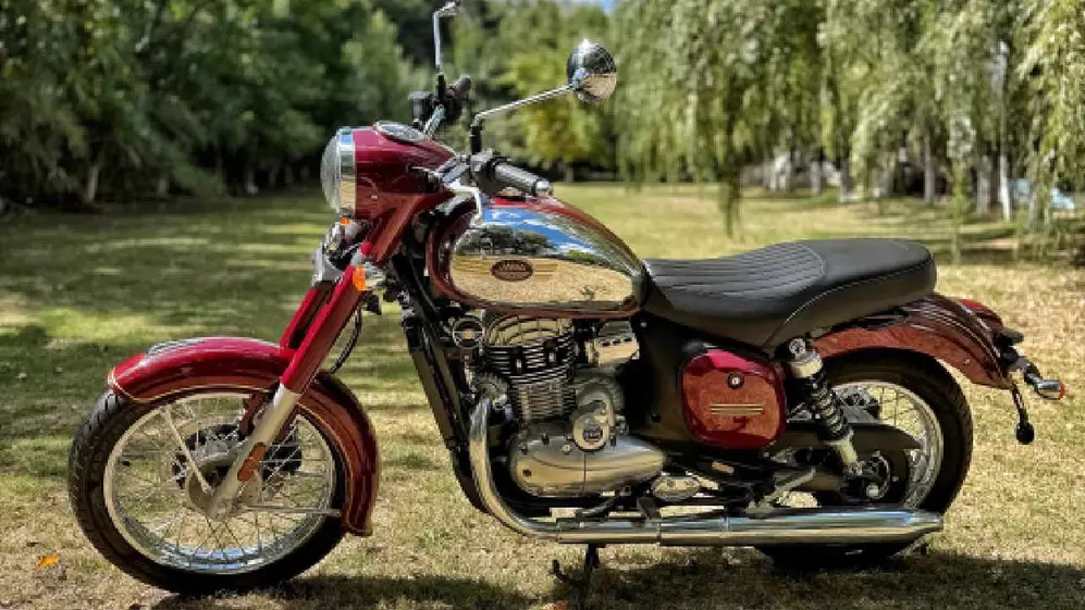 Moto colar roja marca Jawa con asiento negro y partes cromadas estacionada en un predio verde