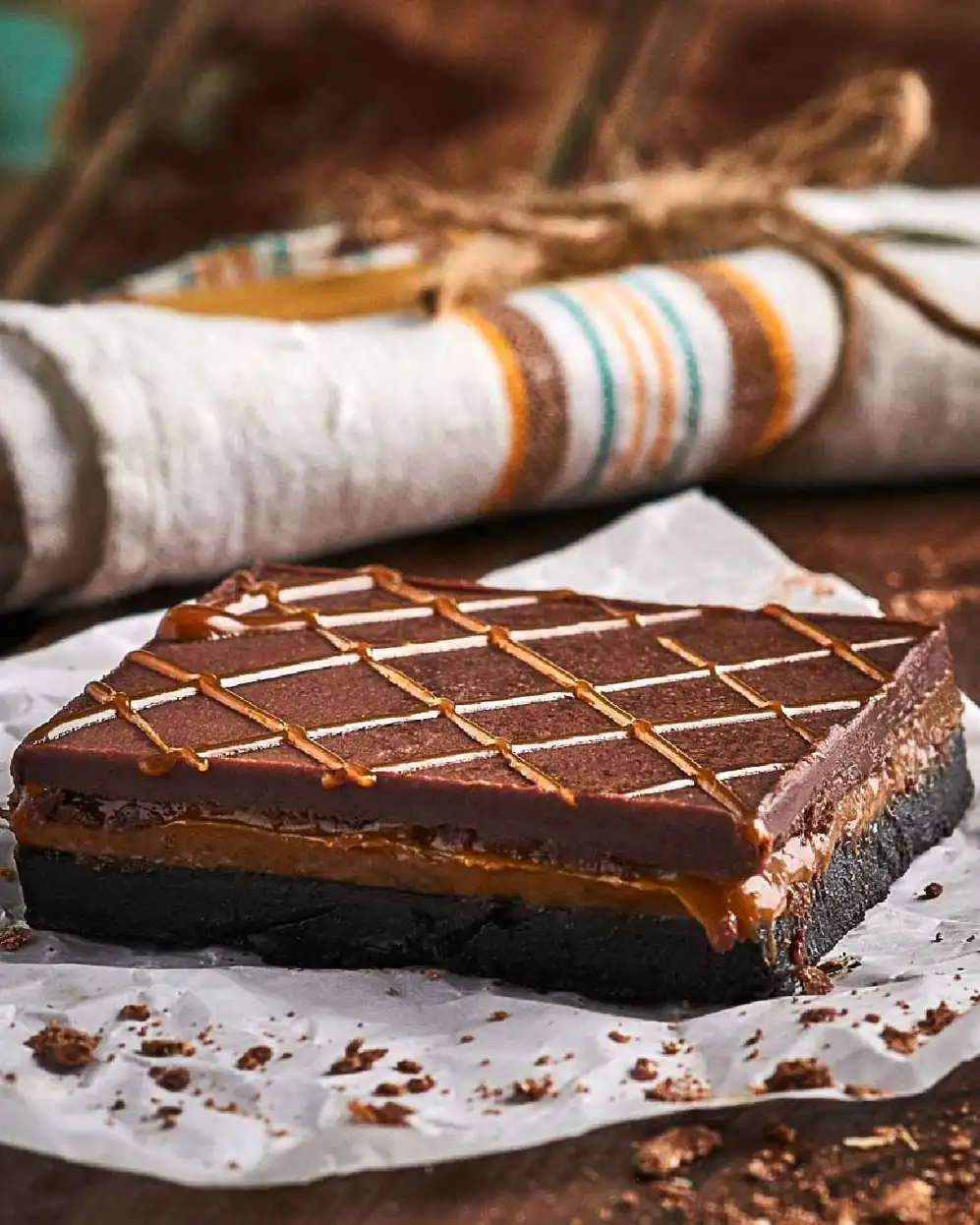 porción de torta con chocolate y dulce de leche con un repasador enrollado atrás