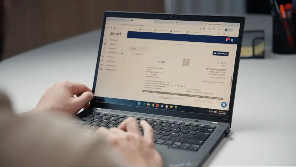 Una notebook arriba de una mesa blanca en cuya pantalla se ve la página web de Xtratc