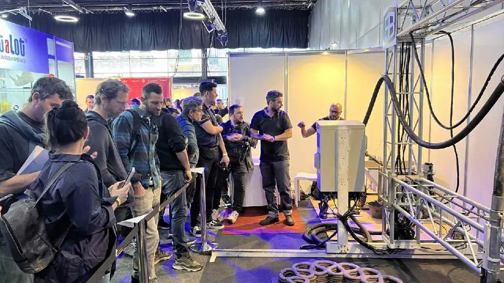 Visitantes observan una demostración de una impresora 3D para construcción en una exposición