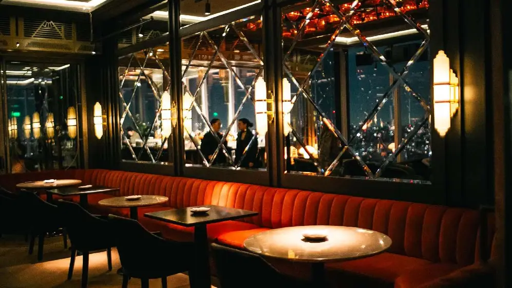 Mesas a lo largo de un sillón rojo iluminado con vistas a la ciudad de buenos aires por atrás