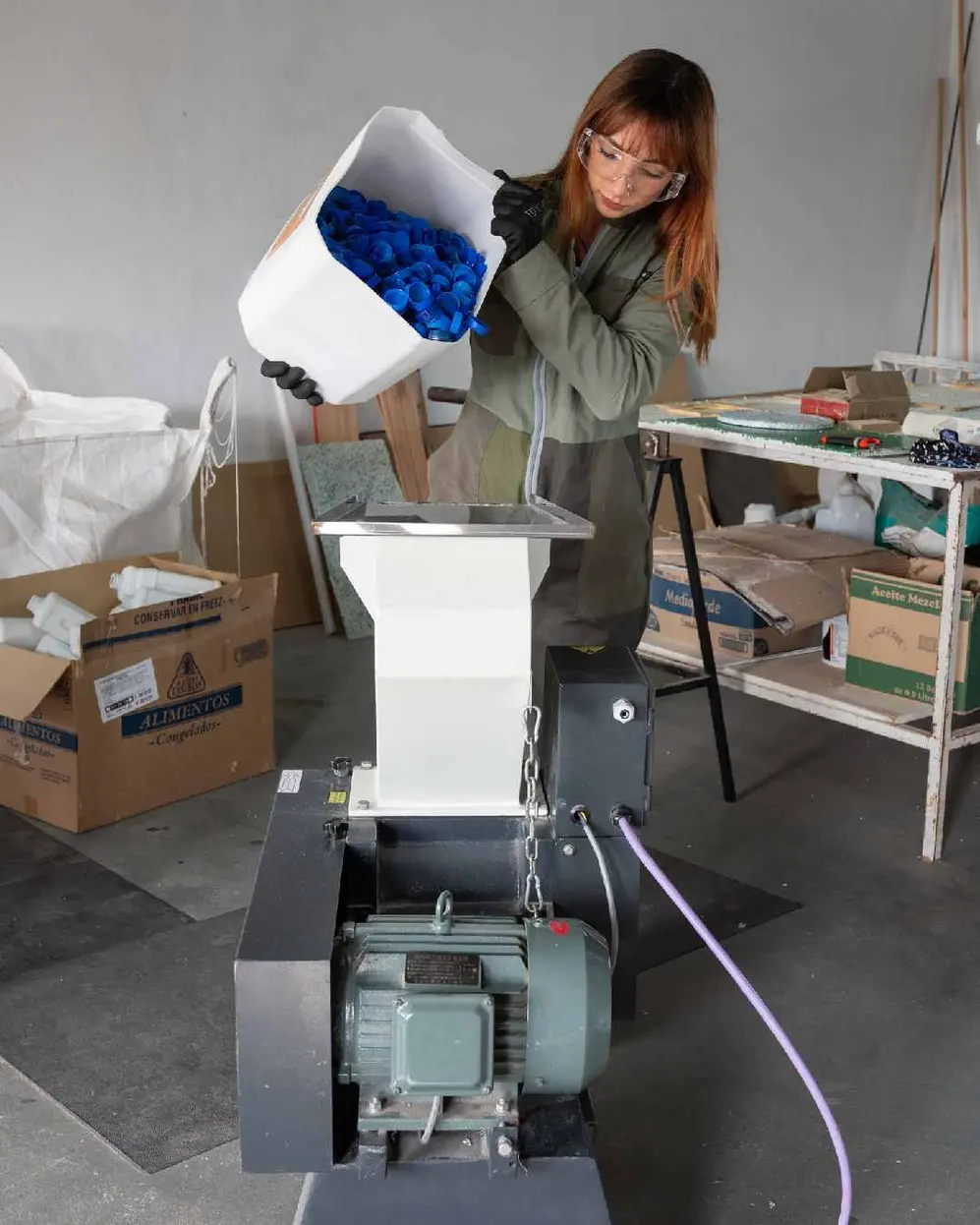 Josefina Diez, la fundadora de la Pyme Marsinplast, tirando muchas tapitas color azul en una máquina
