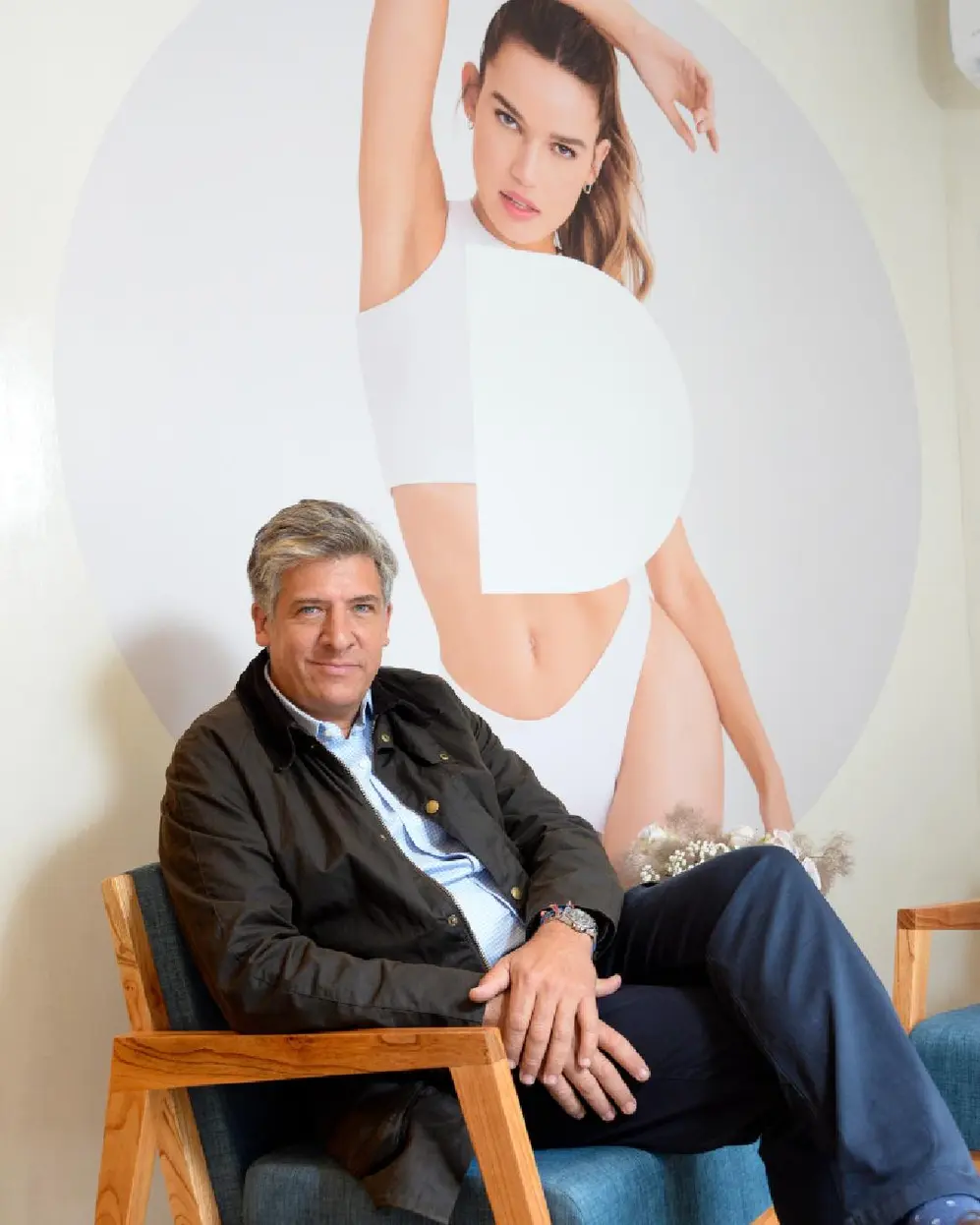 Dueño de Definit sentado en un sillón con una gráfica de una joven atrás