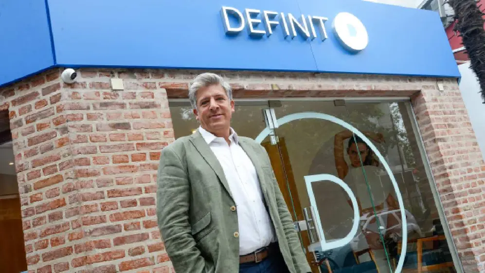El dueño de la cadena Definit con un local de la cadena atrás