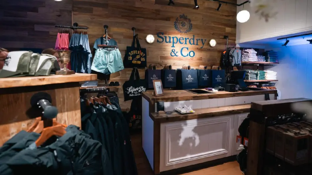 Mostrador, percheros con ropa y decoración en madera en el nuevo local de Superdry en Unicenter