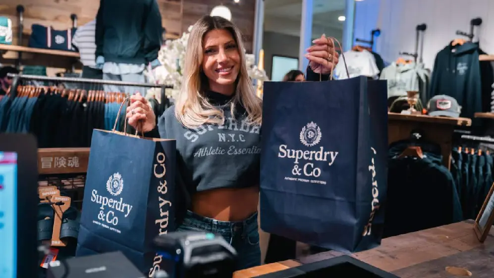 Cale Ruggeri con bolsas azules en sus manos de la marca Superdry en el nuevo local en Unicenter