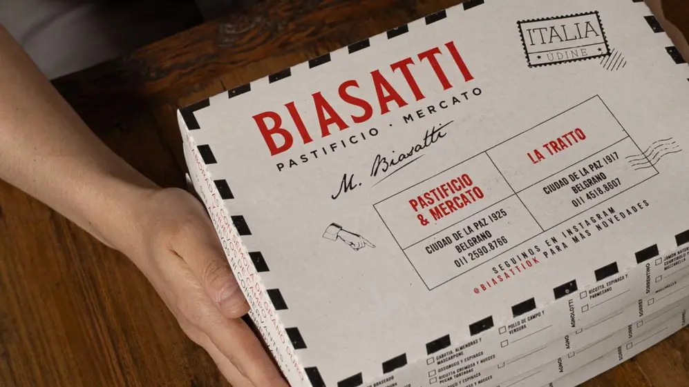 Plano cenital de una persona sosteniendo una caja de empaque de BIASATTI  Pastificio & Mercato