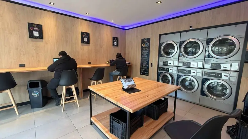 Interior del local de lavander.ia con lavarropas secarropas y espacio de coworking