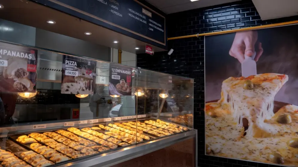 Interior de Sabores Express con vitrina exhibiendo empanadas y cartelería de precios y promos