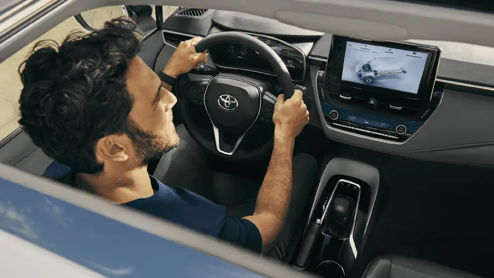 Interior Toyota Corolla con persona manejando. foto oficial.