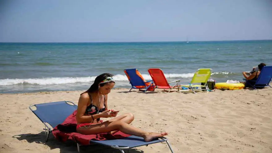 Una mujer utilizando su móvil en la playa, en Italia